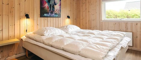 Un dormitorio con cama, paredes de madera, una ventana y un cuadro.