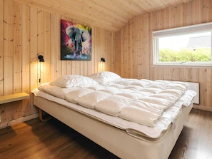 A bedroom with a bed, wooden walls, a window, and a painting. - 4 Star Holiday Home in Idestrup (Idestrup)