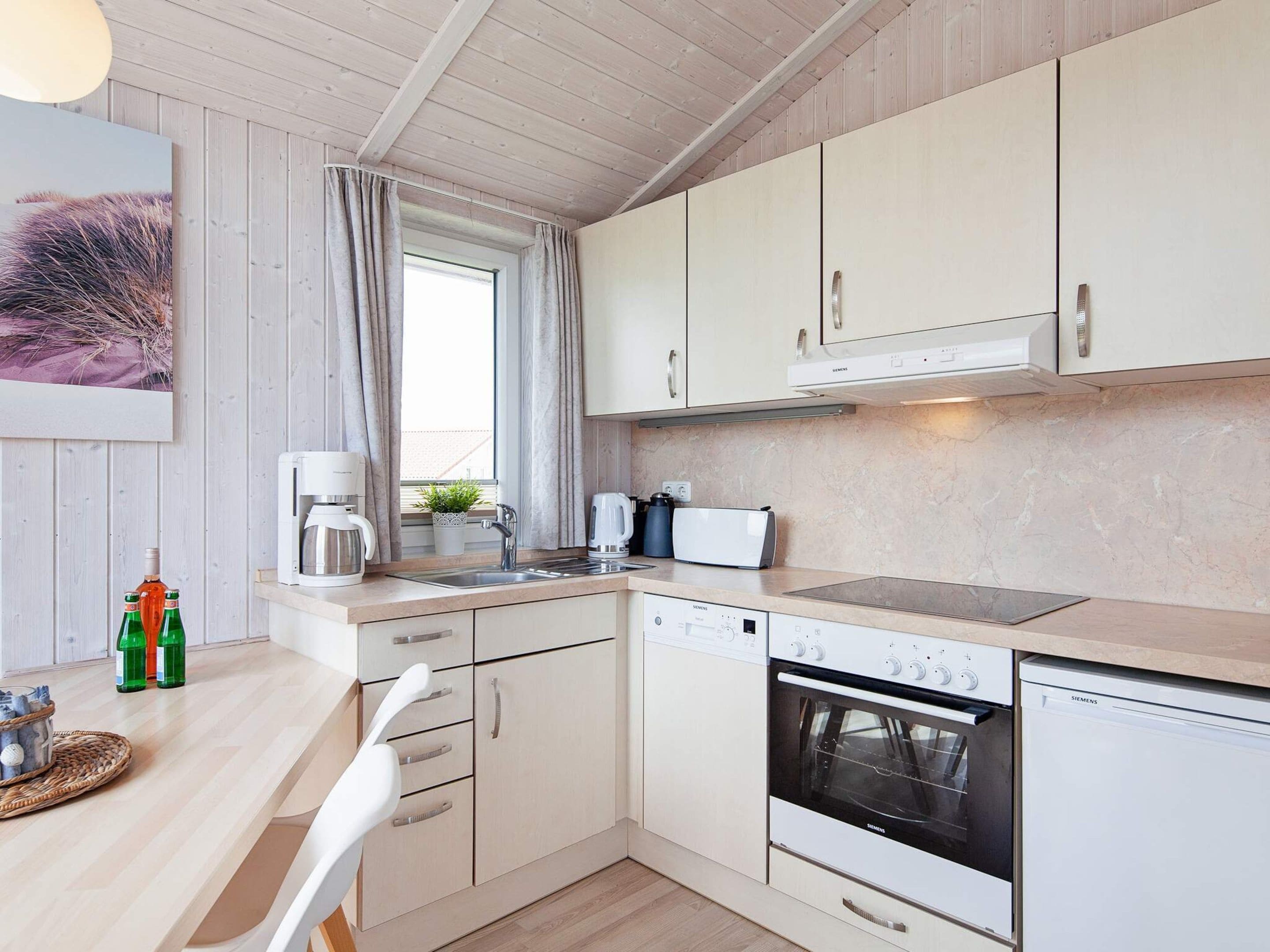 A modern kitchen with white cabinetry, a built-in oven, a dishwasher, and a coffee maker.