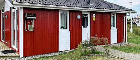 A red building with a tiled roof, a white door, and a small window.