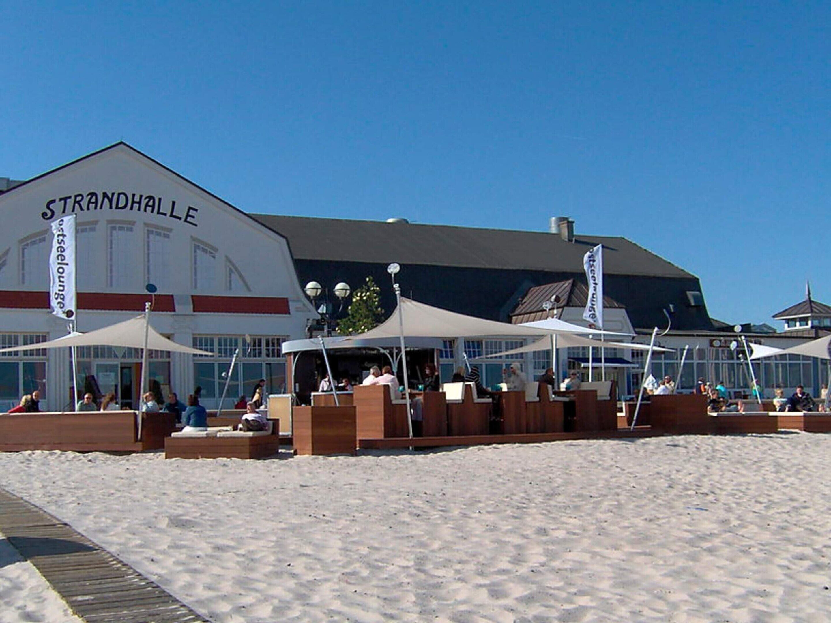 A beachside restaurant with outdoor seating and a building labeled 'STRANDHALLE'.