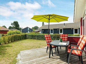 A deck with a table and chairs, an umbrella, and a view of a residential area with houses.