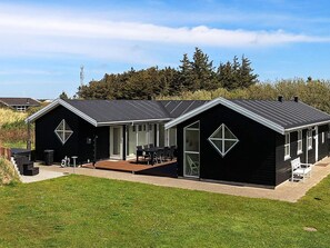 A modern black building with a large patio area, a covered outdoor seating area, and a large window. - Stunning Holiday Home in Hirtshals with Hot Tub (Hirtshals)