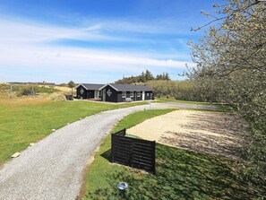 A two-story building with a gravel driveway leading to a wooden gate. - Stunning Holiday Home in Hirtshals with Hot Tub (Hirtshals)