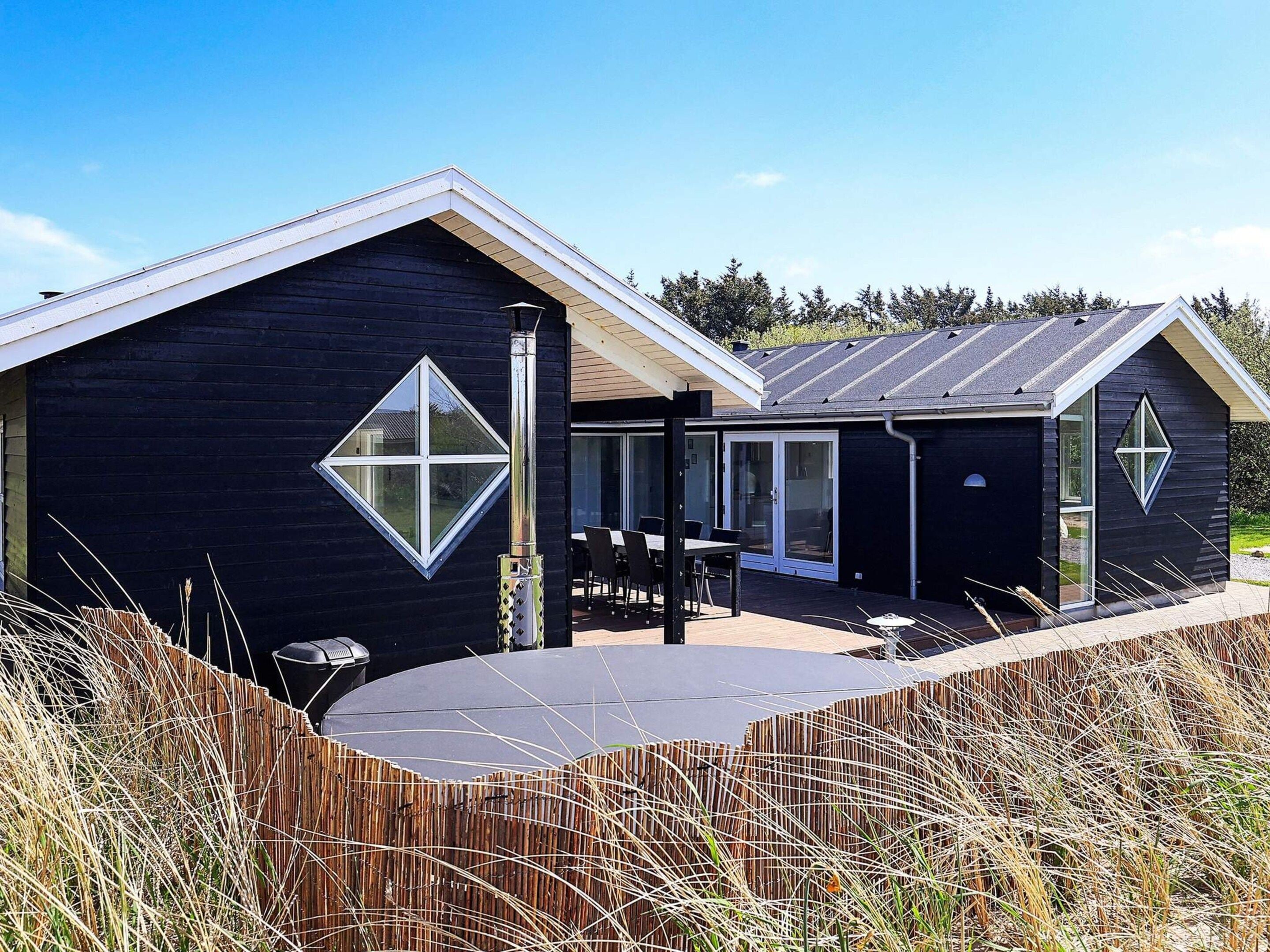 A modern house with a large deck, a covered outdoor seating area, and a garage.