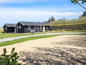 A black building with a gravel driveway and a bench in front. - Stunning Holiday Home in Hirtshals with Hot Tub (Hirtshals)