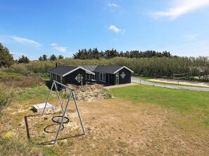 En moderne bygning med sort facade og symmetrisk design, med et stort vindue og en dør.