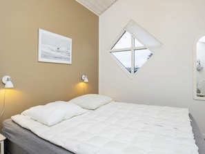 A bedroom with a bed, two bedside lamps, a framed picture on the wall, and a window with a view. - Stunning Holiday Home in Hirtshals with Hot Tub (Hirtshals)