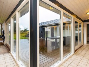 A modern interior with large sliding glass doors leading to an outdoor deck. - Stunning Holiday Home in Hirtshals with Hot Tub (Hirtshals)