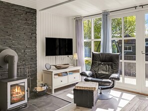 A modern living room with a stone wall, a fireplace, a television, and a comfortable seating area.