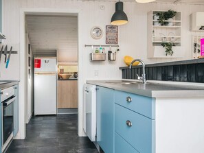 A modern kitchen with blue cabinets, a stainless steel sink, and a black pendant light.