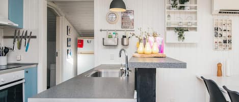 A modern kitchen with a central island, a built-in oven, and a hanging light fixture.