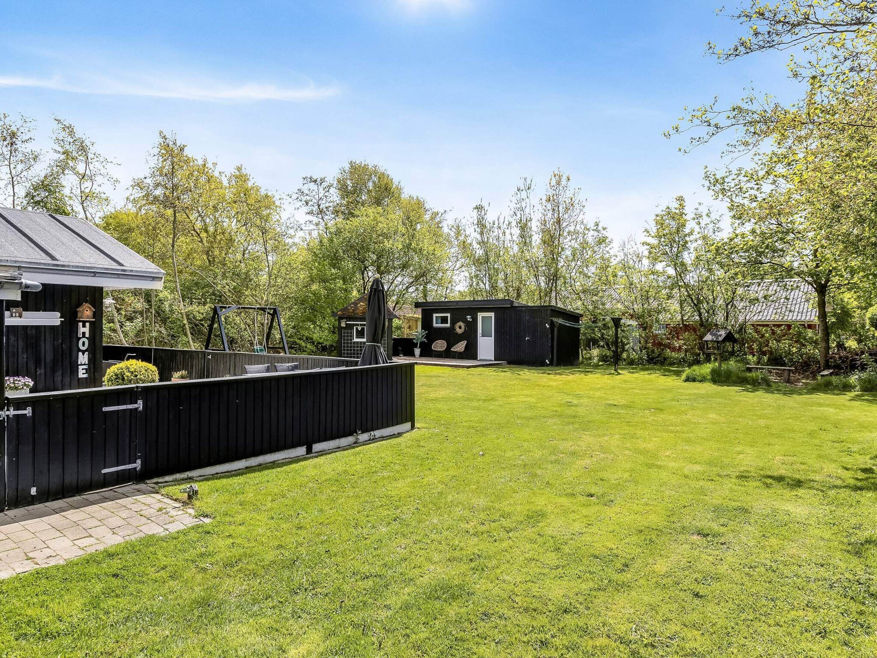 Una propiedad residencial con patio trasero cercado, una casa pequeña y una terraza de madera.