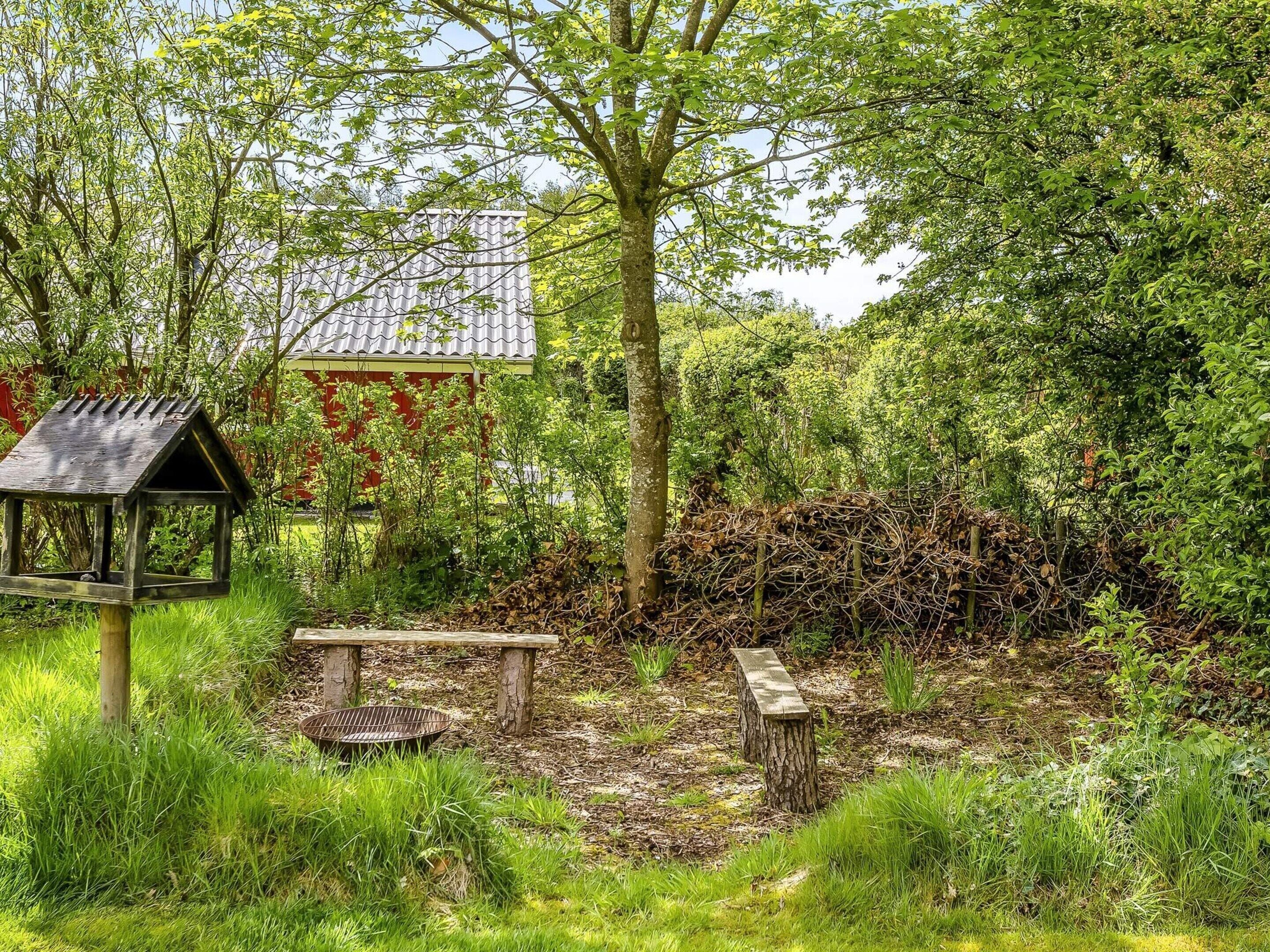 A garden with a bird feeder, a bench, and a small table.
