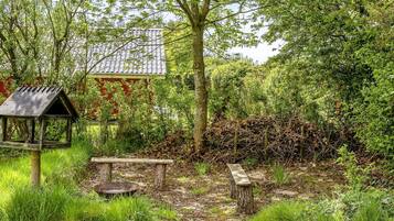 Ein Garten mit Vogelhaus, Bank und kleinem Tisch.