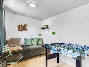 A room with a sofa, a foosball table, a small shelf with items, and a decorative house model on the wall. - 4 Star Holiday Home in Hemmet (Hemmet)