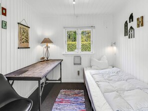A room with a bed, a desk, a lamp, a window with a view of greenery, and wall-mounted decorations. - 4 Star Holiday Home in Hemmet (Hemmet)