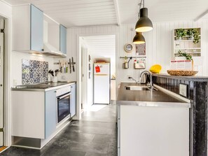 A modern kitchen with a central island, a built-in oven, and a hanging light fixture.