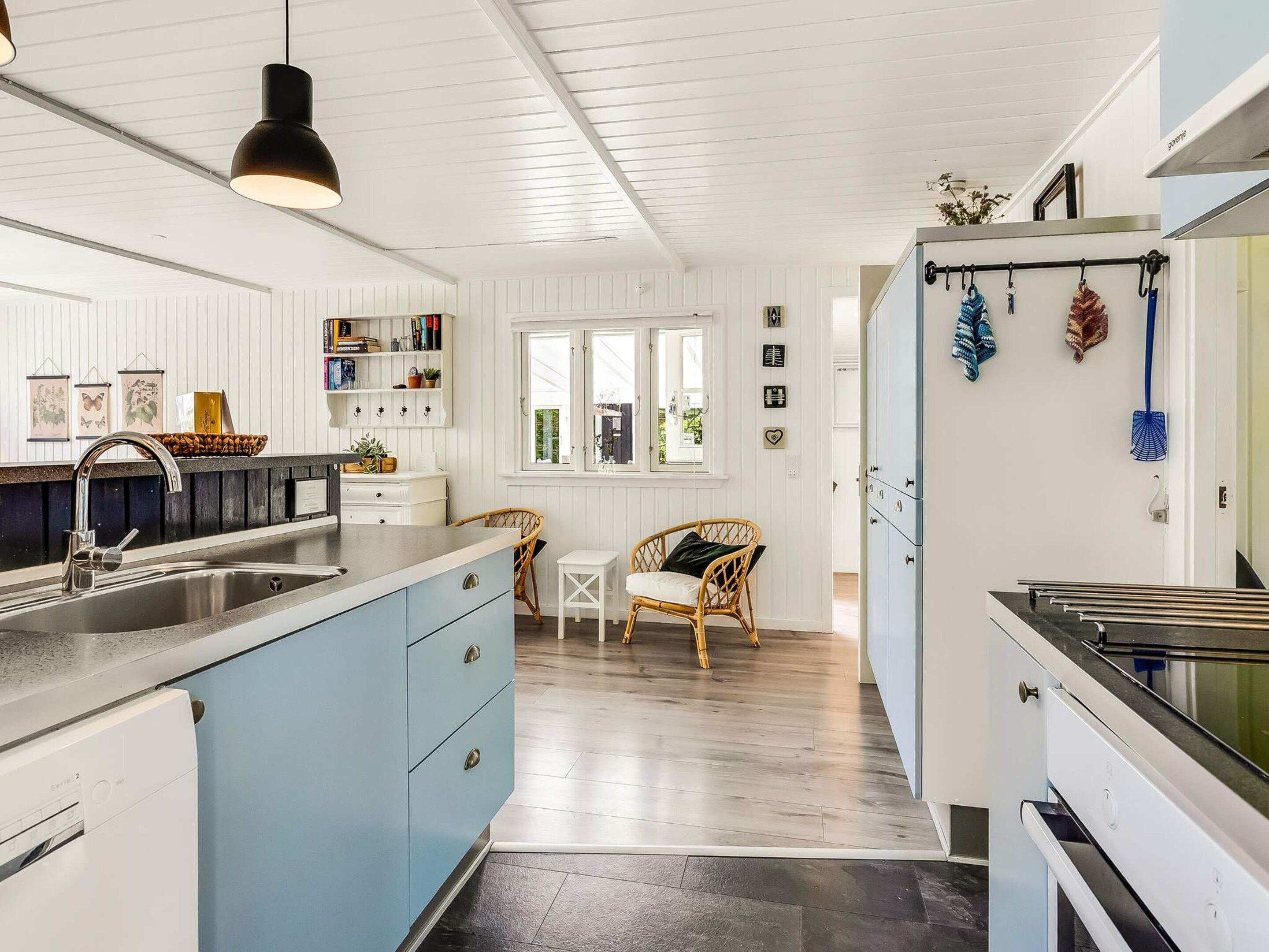 Une cuisine moderne équipée d’un lave-vaisselle intégré, un coin repas avec une chaise et une fenêtre offrant une belle vue.