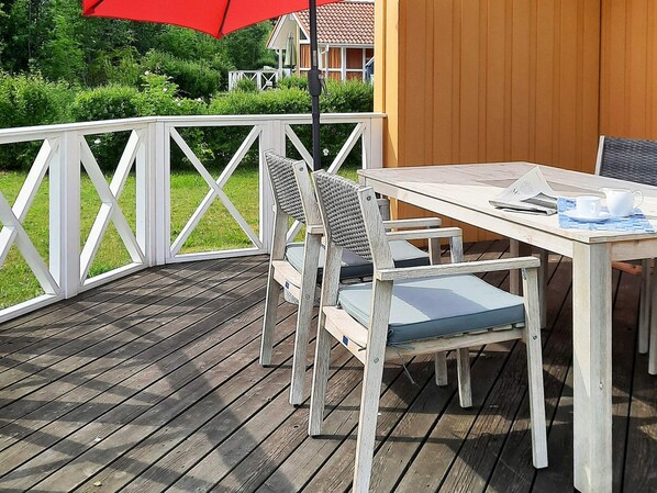 A wooden deck with a white railing, a table, and two chairs.