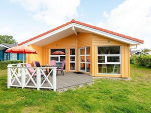 A single-story house with a deck, a covered patio area, and a large window. - Holiday Home in GrÃ¶mmitz (Groemitz)