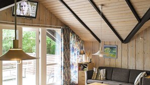 A cozy room with a wooden ceiling, a sofa, a table, and a TV displaying a time. - 8 Person Holiday Home in Vaeggerlose-by Traum (Vaeggerlose)