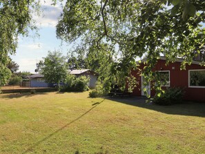 A residential area with a red building, a small shed, and a grassy yard.