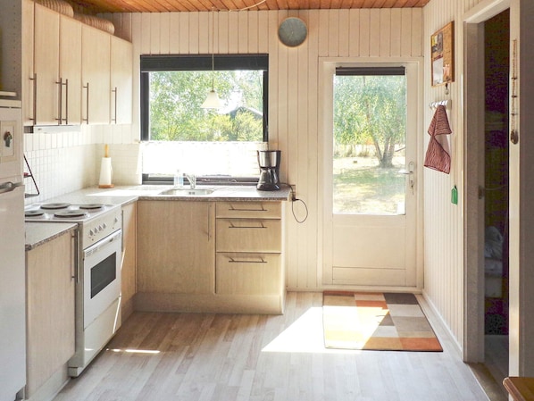 A kitchen with a stove, sink, and window.