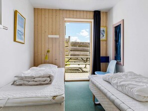 Una habitación con dos camas, una ventana, una puerta que da al exterior y una silla.
