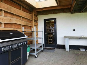 Une cuisine équipée d’un barbecue intégré, d’étagères en métal et d’une porte donnant sur un espace de rangement.