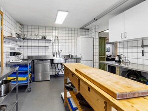 A modern kitchen with stainless steel appliances, a wooden workbench, and blue storage bins. - 24 Person Holiday Home in Lokken (Lokken)