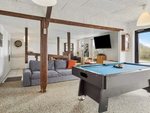 A room with a pool table, a sofa, and a dartboard.