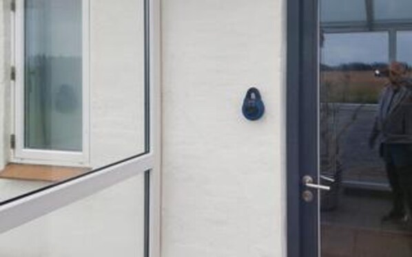 A modern building entrance with a glass door and a keypad lock.
