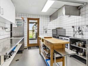 Une cuisine moderne dotée d’appareils électroménagers en acier inoxydable, d’un comptoir en bois et offrant une vue à travers la porte.