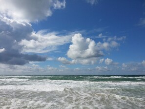 Une plage avec des vagues et un ciel partiellement nuageux.