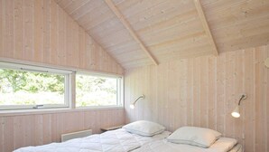 A bedroom with a large bed, wooden walls, and a window providing natural light. - 8 Person Holiday Home in Idestrup-by Traum (Idestrup)
