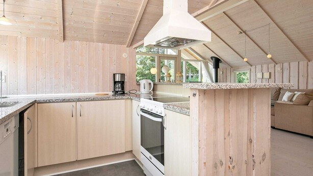 A modern kitchen with wooden cabinetry, a built-in oven, and a coffee maker. - 8 Person Holiday Home in Idestrup-by Traum (Idestrup)