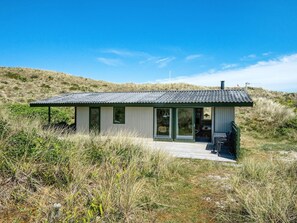Une maison moderne de plain-pied, dotée d’un toit plat, de grandes portes-fenêtres coulissantes et d’un petit patio.