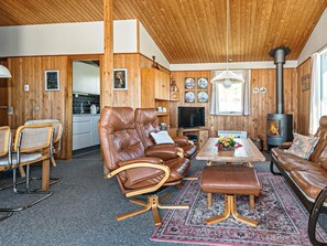 A cozy cabin interior with wooden walls and a central seating area featuring leather sofas and chairs. - 5 Person Holiday Home in Ringkobing (Ringkobing)
