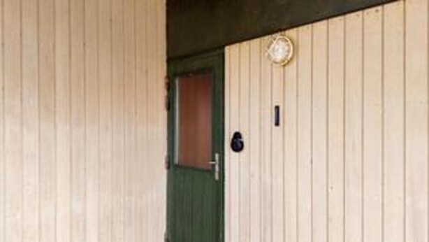 A wooden door with a green frame, a small circular window above it, and a black doorbell button to the right. - 5 Person Holiday Home in Ringkobing (Ringkobing)