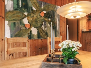 Une table de salle à manger en bois, agrémentée d’un chandelier et de fleurs.