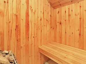 Un sauna en bois avec un banc et un mur en pierre.