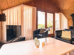A wooden-paneled room with a TV, two leather chairs, a table, and a fireplace. - 4 Star Holiday Home in Idestrup (Idestrup)