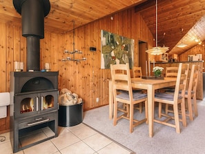 A wooden interior with a fireplace, dining table, chairs, and a painting on the wall. - 4 Star Holiday Home in Idestrup (Idestrup)