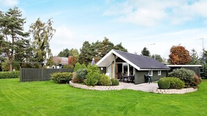 Une maison de plain-pied dotée d’un patio, entourée d’une pelouse bien entretenue et d’une clôture en bois.