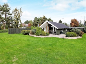 Une maison de plain-pied dotée d’un patio, entourée d’une pelouse bien entretenue et d’une clôture en bois.