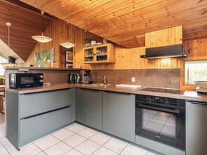 Une cuisine moderne avec un revêtement mural en bois, un four à micro-ondes encastré, une machine à café et un lave-vaisselle.