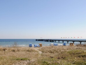 A coastal scene with a pier extending into the sea, a sandy beach, and a grassy area. - Holiday Home in GroÃŸenbrode (Grossenbrode)