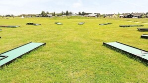 En gräsklädd äng med flera gröna picknickbord uppställda i rader.