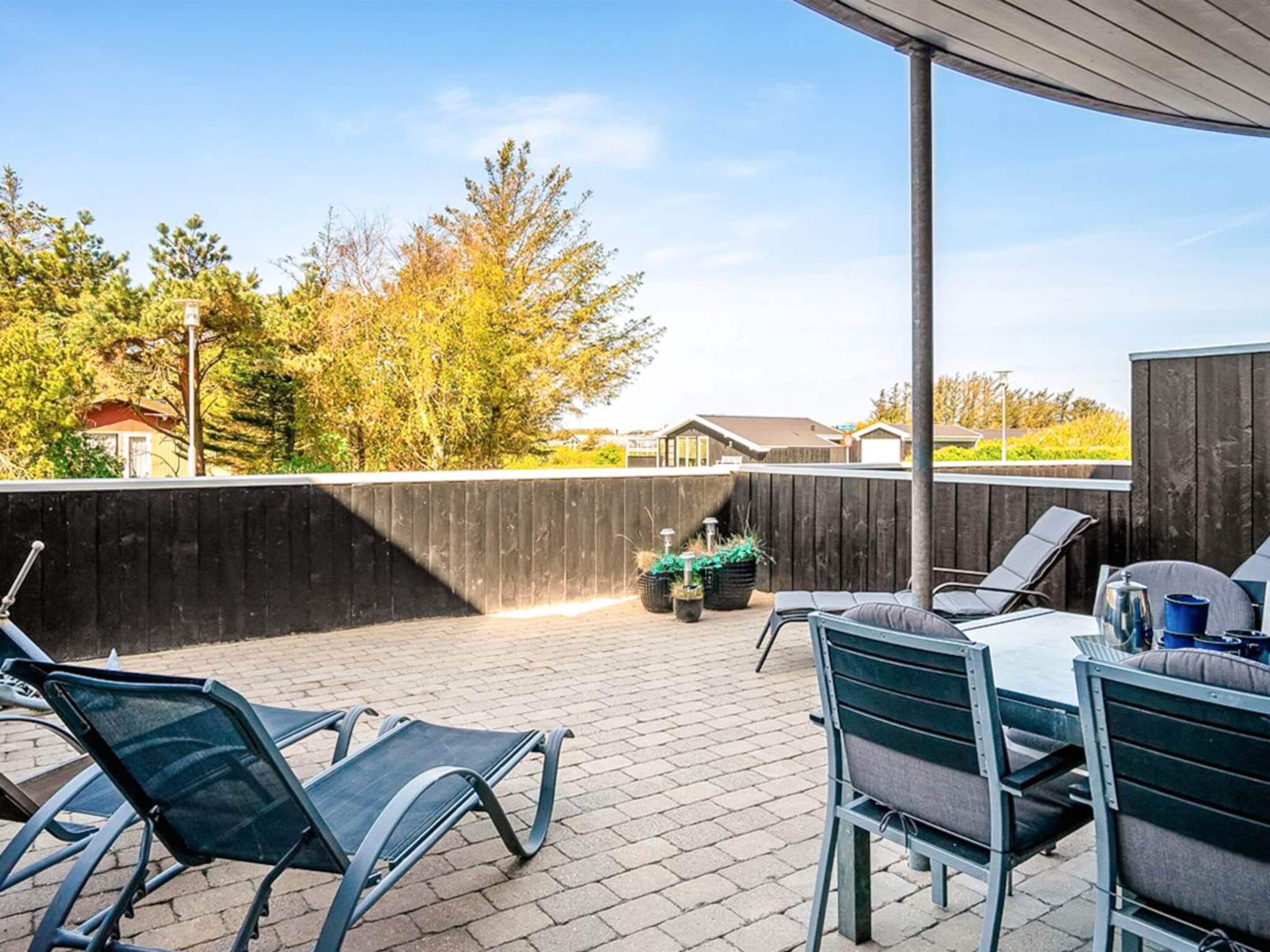 An outdoor patio with a covered area, seating, and a view of the surrounding landscape.